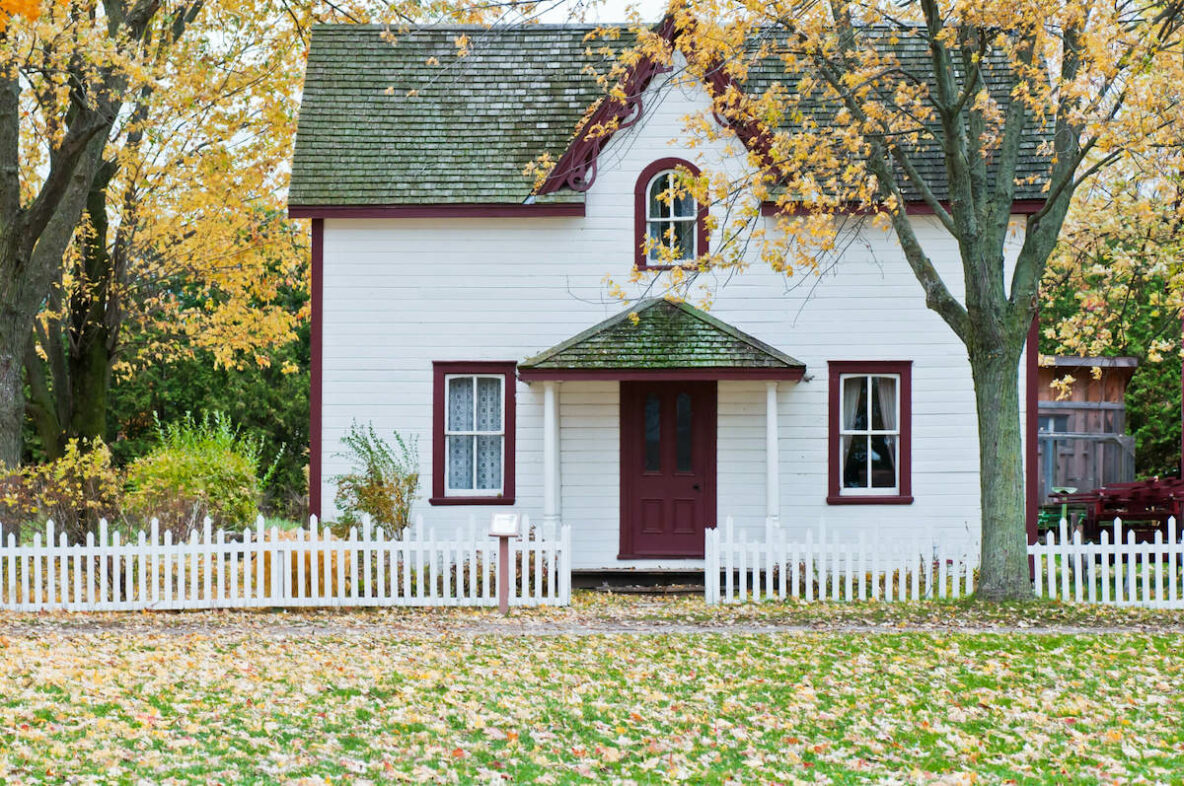 White cottage with leaves on the ground
